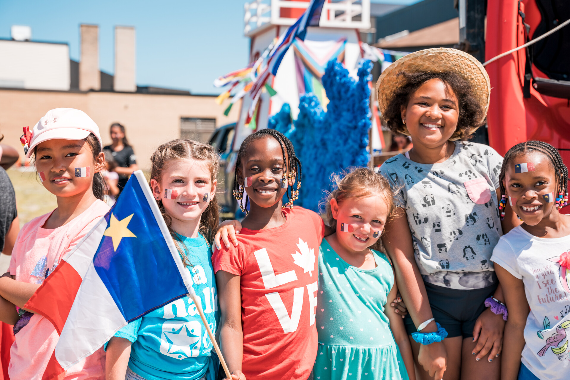 A picture of young girls from various backgrounds together in front of a parade float.